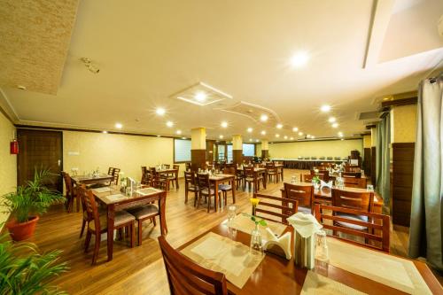 un restaurante con mesas de madera y sillas de madera en Midtown Suites Marathahalli Bangalore, en Bangalore