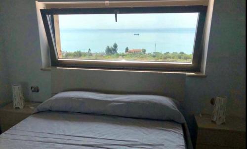 um quarto com uma cama e uma janela grande em Appartamento vista mare a Trebisacce em Trebisacce