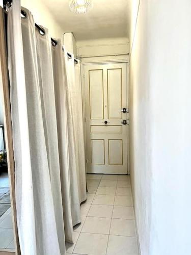 un couloir avec des rideaux blancs et une porte blanche dans l'établissement Studio de charme hyper centre, à Nice