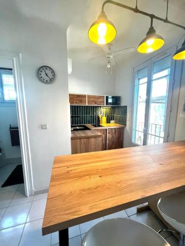 une cuisine avec une table en bois et une horloge au mur dans l'établissement Studio de charme hyper centre, à Nice