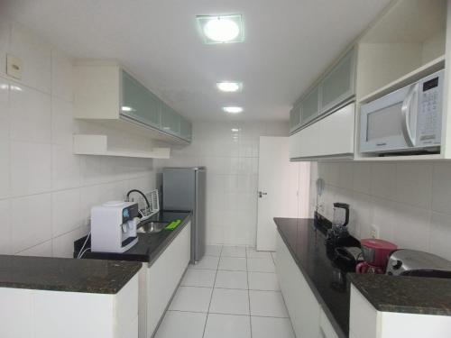 a small kitchen with a sink and a microwave at Apartamento 2 quartos Prédio frente Para o Mar início da Praia do Morro in Guarapari