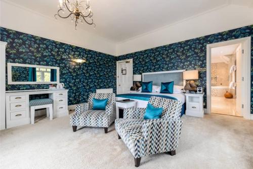 a bedroom with a bed with blue walls and two chairs at Applegarth Villa Hotel & Restaurant (Adult Only) in Windermere