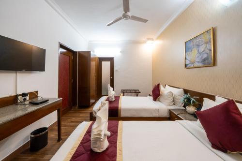 a hotel room with two beds and a couch at Lords Midtown Suites Bangalore in Bengaluru