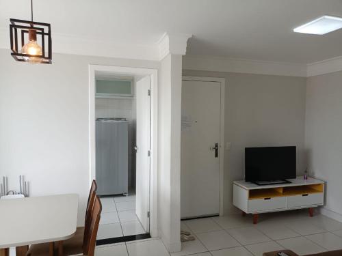 una sala de estar con TV en un armario y una mesa en Apartamento Pé na Areia, Wi-Fi e Garagem Privativa início da Praia do Morro en Guarapari