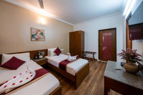 a hotel room with two beds and a desk at Lords Midtown Suites Bangalore in Bengaluru