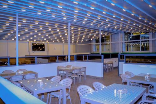 un restaurante con mesas, sillas blancas y luces en Jees Hotel, en Hargeysa