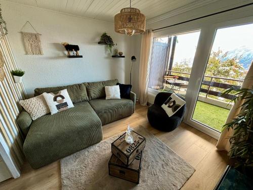 a living room with a green couch and a large window at Vue imprenable sur les Alpes et Parking privé gratuit in Crans-Montana