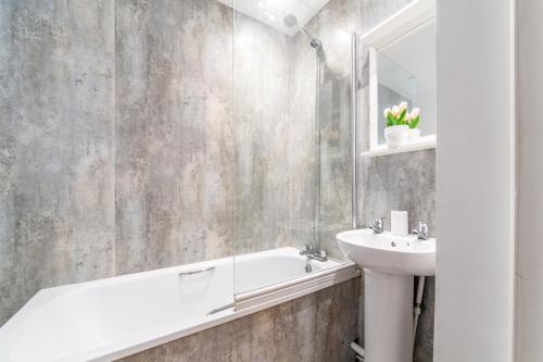 a bathroom with a sink and a bath tub and a mirror at The Hackney Luxury Flats in London