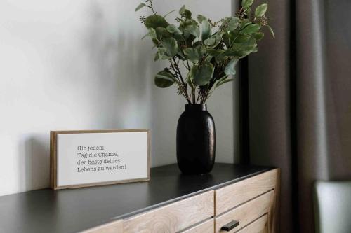 a black vase with flowers on top of a dresser at Gropius in Dessau