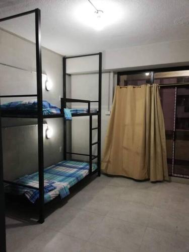 マニラにあるManila Real Residences Studio 8Bの二段ベッド3組とカーテンが備わる客室です。