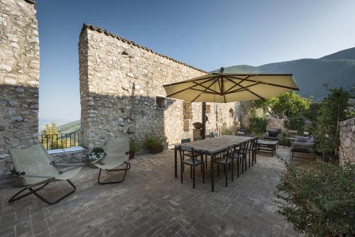 a patio with a table and chairs and an umbrella at Relais Borgo Campello in Campello sul Clitunno