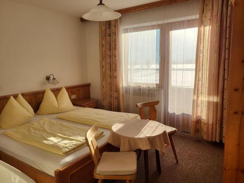 1 dormitorio con cama, mesa y ventana en Appartements Binderhof, en Kirchdorf in Tirol