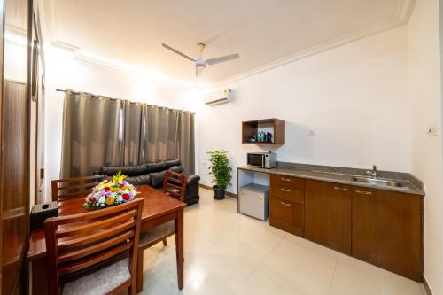 a living room with a dining room table and a kitchen at Lords Midtown Suites Bangalore in Bengaluru