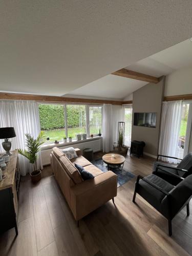 a living room with a couch and a table at Gezellige, luxe bungalow 't pareltje in het bos in Hardenberg "Rheezerveen"woning 20 in Rheezerveen