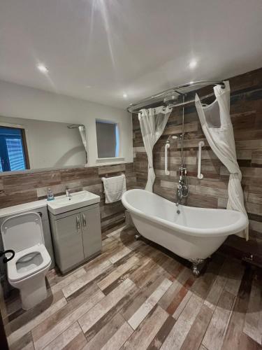 a bathroom with a tub and a toilet and a sink at The Birch Lodge located in Pegsdon in Hexton