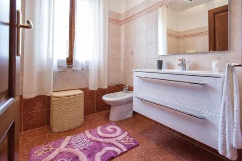 uma casa de banho com um lavatório, um WC e um espelho. em Alghero Villa Mistral per 7 persone Terrazza BBQ AC WiFi em Alghero