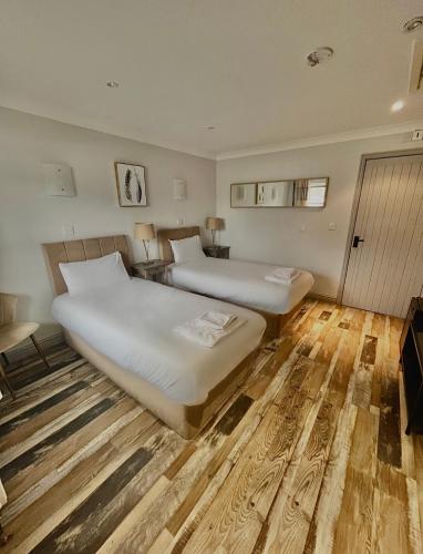 two beds in a room with wood flooring at Aspen, Country Chalet located In Pegsdon in Hexton