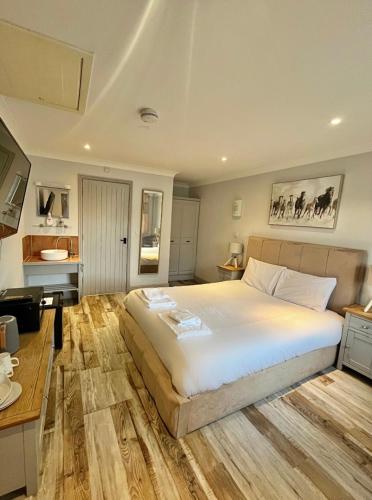 um quarto com uma grande cama branca e piso em madeira em Beech, Country Chalet In Pegsdon em Hexton