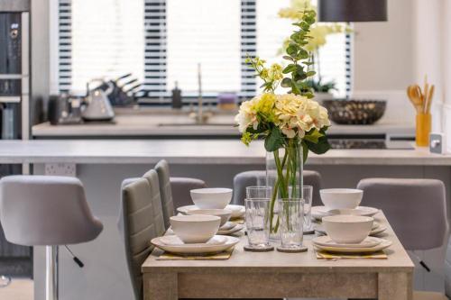 a table with a vase of flowers on it at New, modern 4 bed, 3 bath house ,free parking in Oxford
