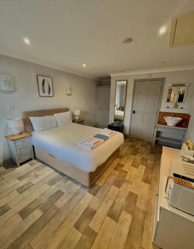 a bedroom with a large white bed and wooden floors at Oak, Country chalet located in Pegsdon in Hexton