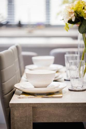 a table with plates and bowls and a vase of flowers at New, modern 4 bed, 3 bath house ,free parking in Oxford
