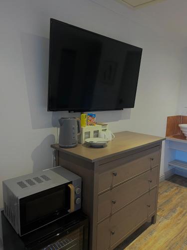 a tv on top of a wooden dresser with a microwave at Pine, Country chalet located in Pegsdon in Hexton