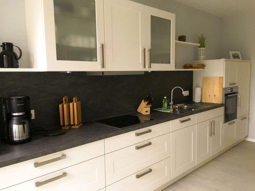 a kitchen with white cabinets and a black counter top at Landhaus Scholz in Dollerup
