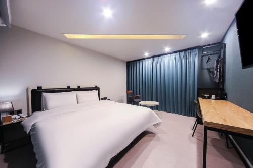 a bedroom with a large white bed and a desk at Daeyeon ONNA Hotel in Busan