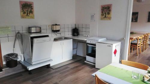 a kitchen with white appliances and a table and chairs at Harzklub Wanderheim in Wildemann