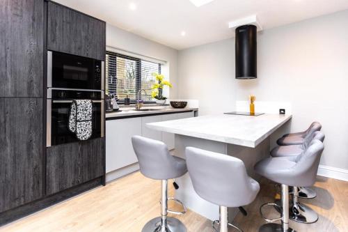 a kitchen with a large island with white counter chairs at New, modern 4 bed, 3 bath house ,free parking in Oxford