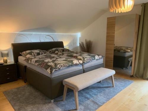 a bedroom with a bed and a stool and a mirror at Habicht Ferienhaus in Arnbruck