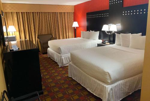 a hotel room with two beds and a chair at Ramada by Wyndham Rochelle Park Near Paramus in Rochelle Park