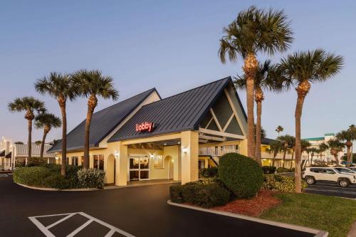 a hotel with palm trees in a parking lot at Days Inn by Wyndham Cocoa Beach Port Canaveral in Cocoa Beach