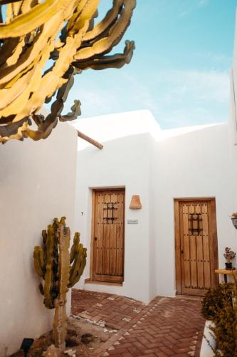 a white building with wooden doors and a cactus at Cortijo Los Malenos in Agua Amarga