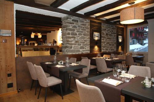 a restaurant with tables and chairs and a stone wall at Lifestyle & Spa Hotel Grächerhof in Grächen
