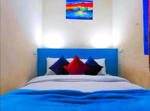 uma cama azul com almofadas vermelhas e azuis em Dar merouan em Essaouira