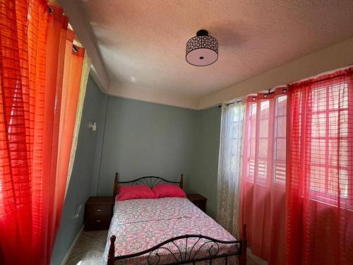 1 dormitorio con 1 cama con cortinas rojas y naranjas en Hygge's Inn, en Roseau
