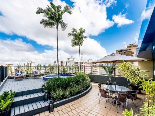 d'un balcon avec des tables, des chaises et des palmiers. dans l'établissement Grand Mercure Belem do Para, à Belém