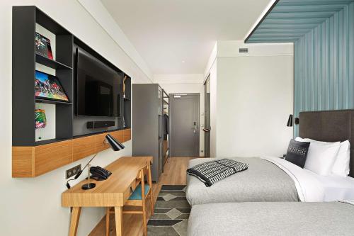 a bedroom with a bed and a tv on a wall at Canopy by Hilton Reykjavik City Centre in Reykjavík