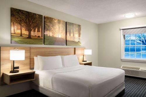 a hotel room with a white bed and a window at Days Inn & Suites by Wyndham Lancaster Amish Country in Lancaster