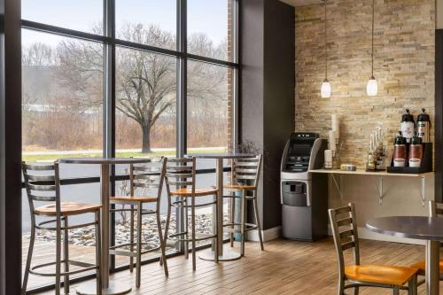 a bar with tables and chairs in a room with windows at Days Inn & Suites by Wyndham Lancaster Amish Country in Lancaster