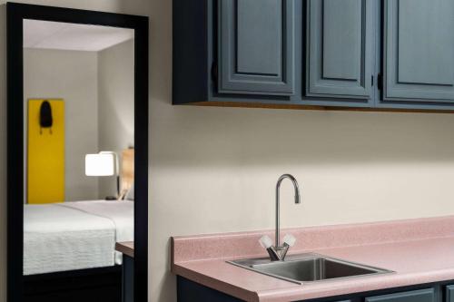 a kitchen counter with a sink and a mirror at Days Inn & Suites by Wyndham Lancaster Amish Country in Lancaster