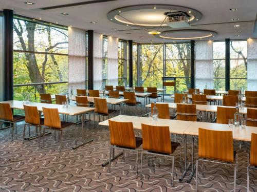 a dining room with tables and chairs and windows at Mövenpick Hotel Hamburg in Hamburg