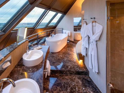 y baño con 2 lavabos y ducha. en Mövenpick Hotel Hamburg en Hamburgo