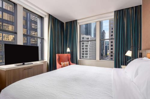 Hilton Garden Inn- Chicago Central Loop في شيكاغو: غرفة فندقية بسرير وتلفزيون بشاشة مسطحة
