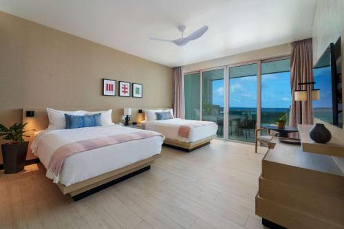 a hotel room with two beds and a large window at Wyndham Grand Barbados Sam Lords Castle All Inclusive Resort in Saint Philip