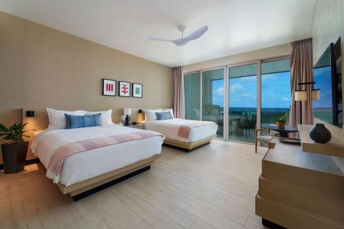 サンフィリップにあるWyndham Grand Barbados Sam Lords Castle All Inclusive Resortのベッド2台と大きな窓が備わるホテルルームです。