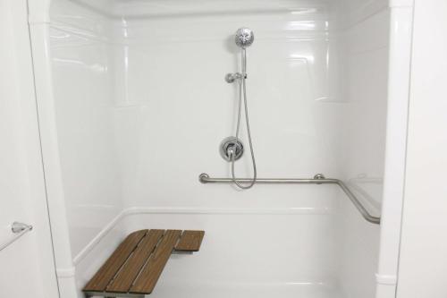 a bathroom with a bathtub with a wooden bench in it at Days Inn by Wyndham Stony Plain in Stony Plain