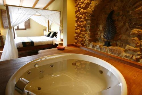 a bath tub in a room with a bedroom at Masía Durbá B&B in Castellnovo