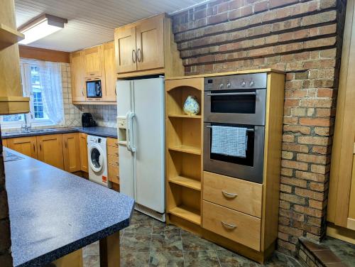 a kitchen with a white refrigerator and a brick wall at The Old Fire House in Thetford